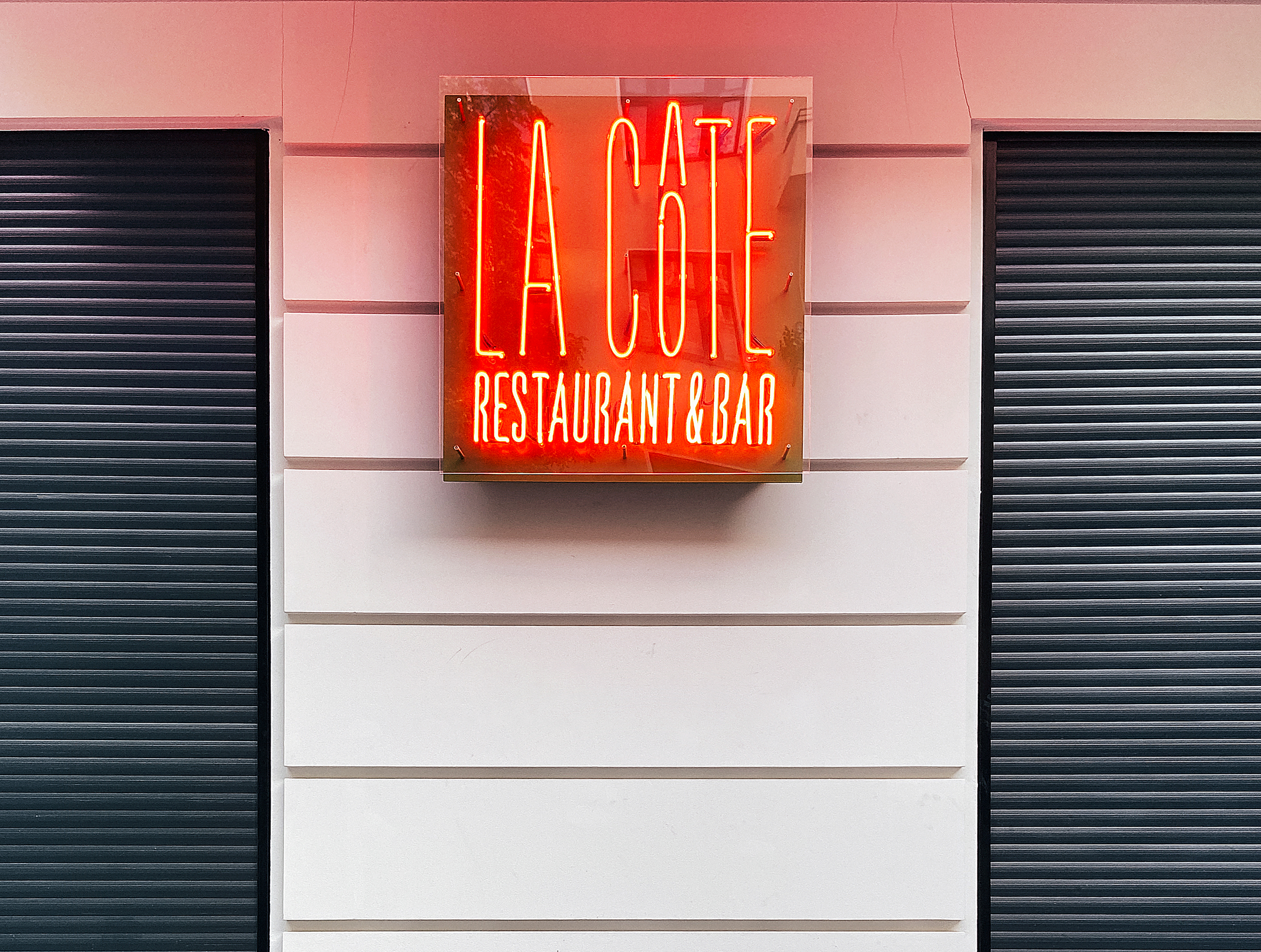 La Côte's neon storefront sign"